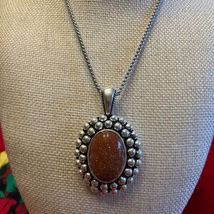 GOLD STONE SET IN DETAILED SILVER PENDANT.
